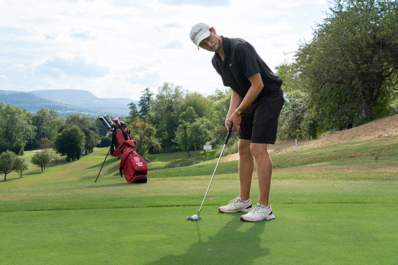 Ein Golfspieler führt auf dem grün einen Schlag aus, kurz vor dem Loch.